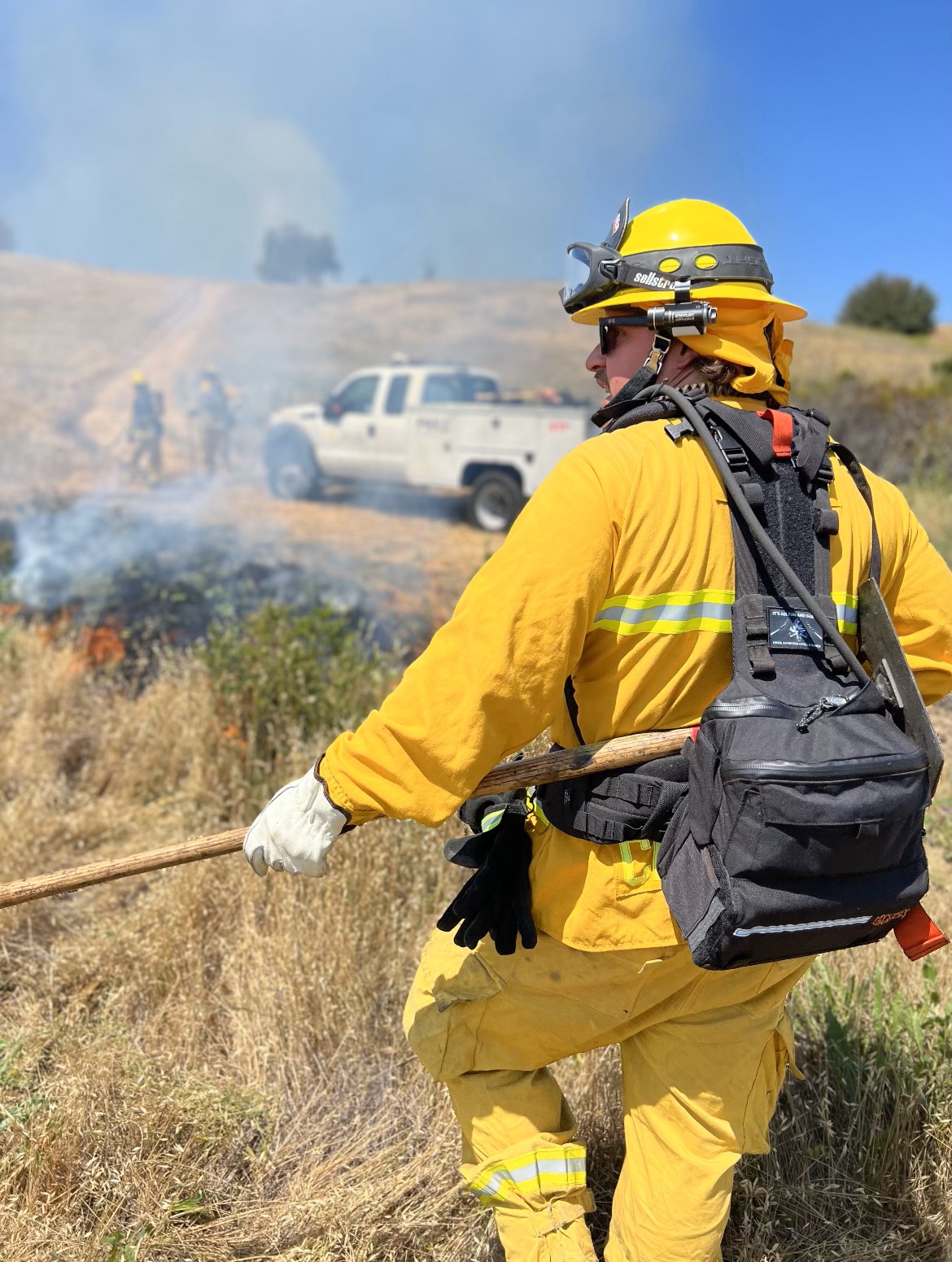 A firefighter works a controlled burn in a grassy field